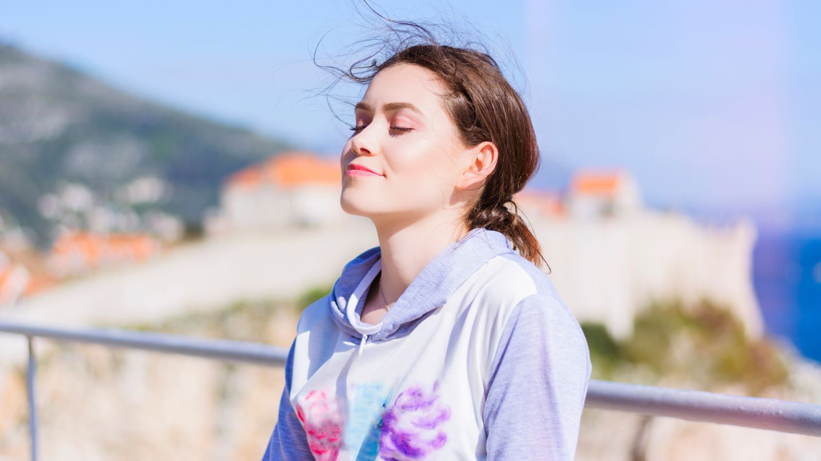 A woman resting on a railing inhaling peacefully