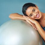 A fit and happy woman resting on an exercise ball