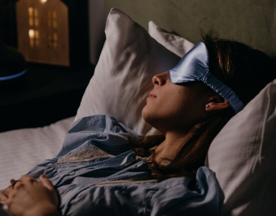 A woman trying to have a good night's sleep by using a sleeping eye mask to protect her eyes from bright light
