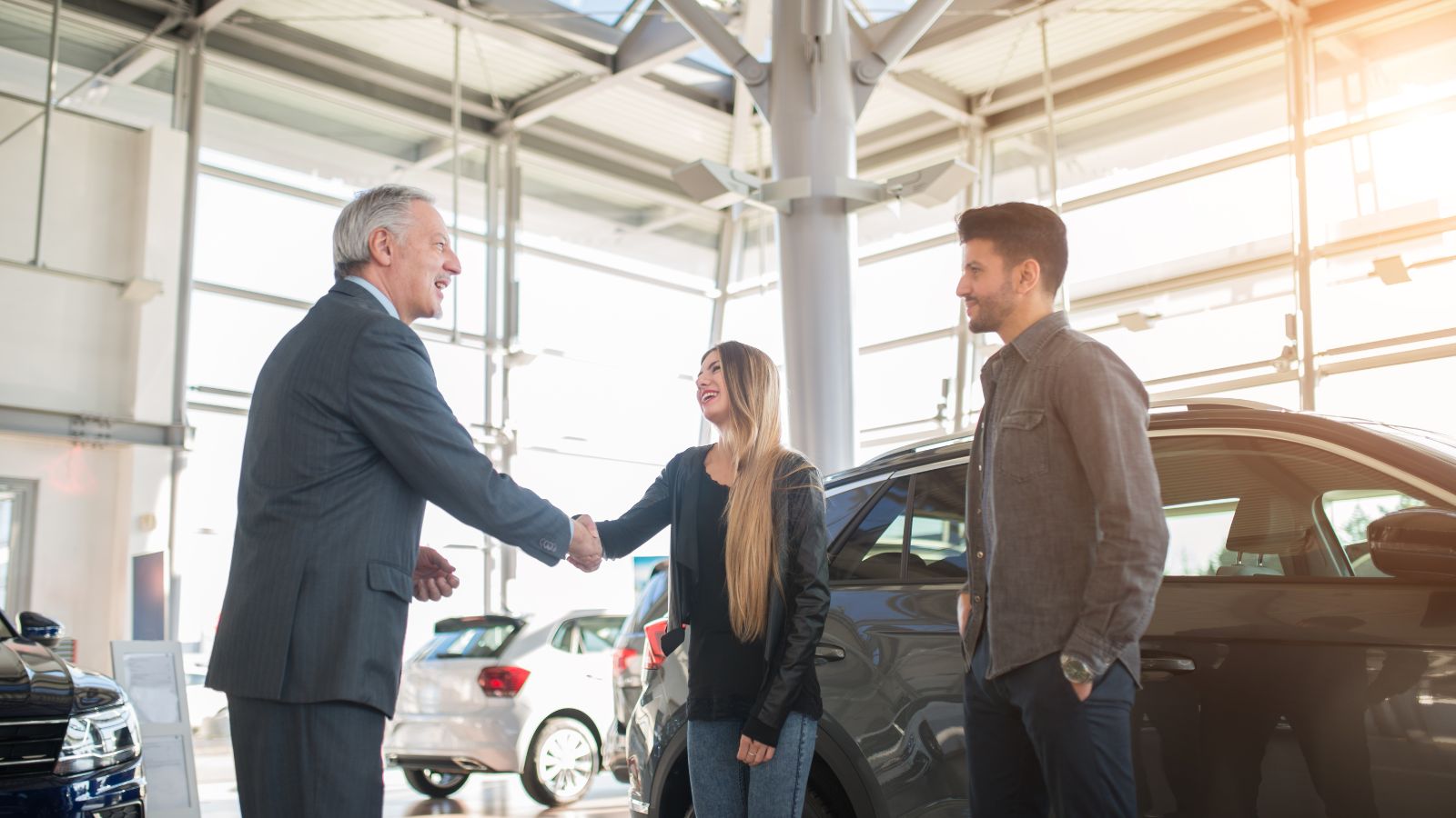 A car salesman shaking hands with clients after making a car deal