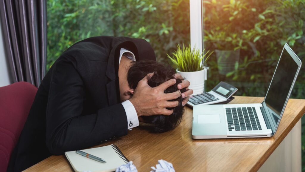 Frustrated small business man resting his head on the desk struggling with a failing business
