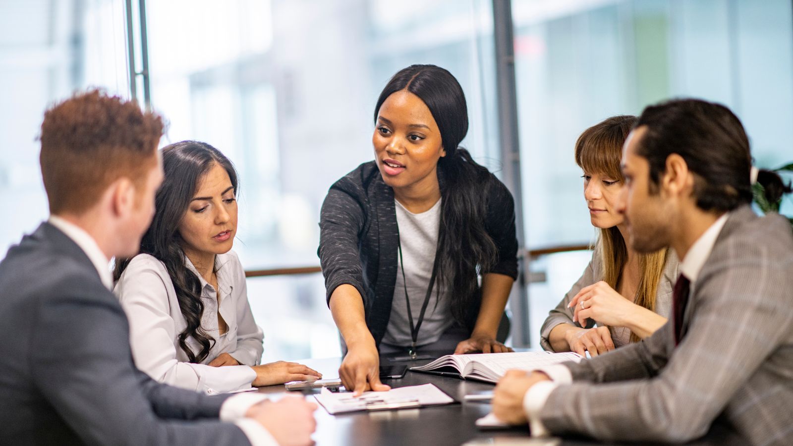 A business manager reflecting a successful servant leadership having a meeting with her team