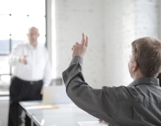 Male employee raising hand to ask a question in the office boardroom
