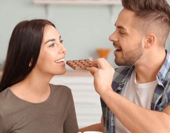 A man feeding his wife chocolate bars
