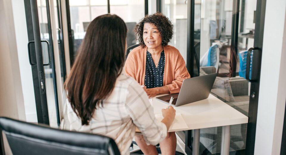 two ladies at desk talking hiring